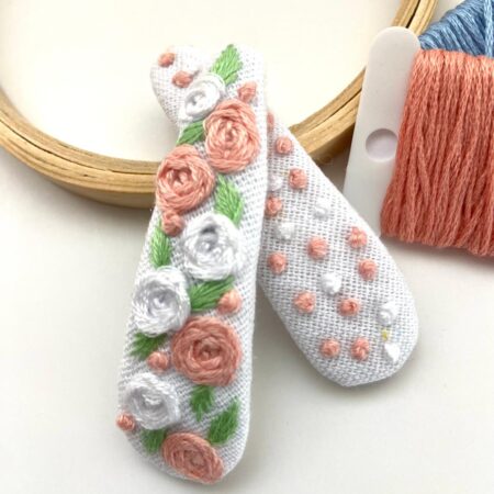 Hand-embroidered hair clips in soft peach with white roses and tiny pearl accents.