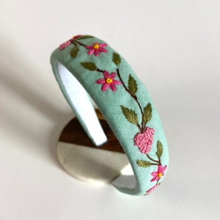 Light green linen headband hand-embroidered with pink floral details inspired by springtime freshness.