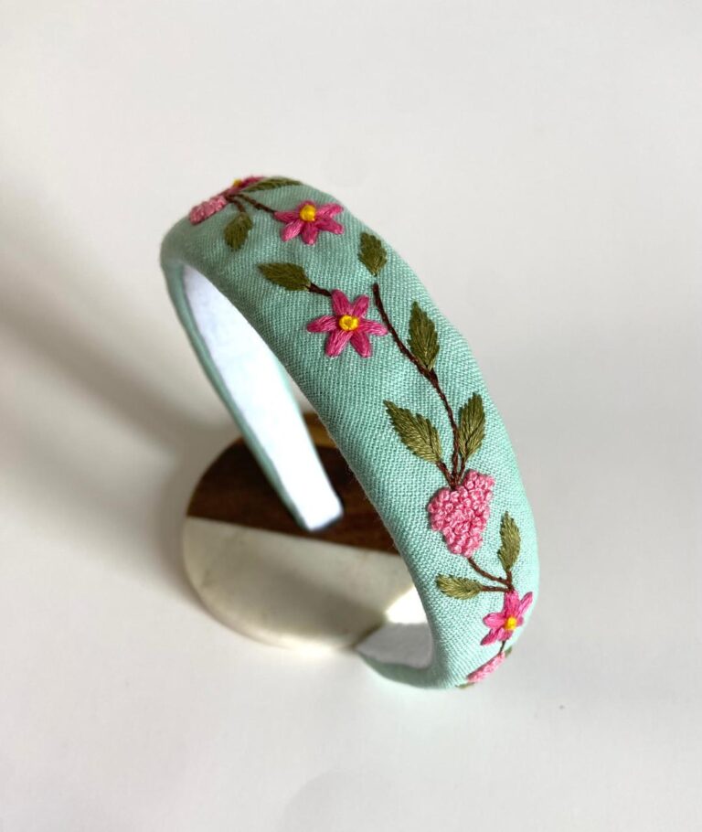 Light green linen headband hand-embroidered with pink floral details inspired by springtime freshness.