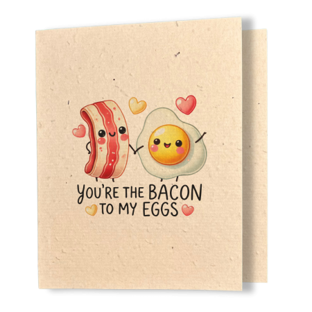 plantable greeting card, natural coloured paper, embedded with wildflower seeds, an image in kawaii style of a slice of bacon and an egg holding hands, the sentiment on the card reads, you're the bacon to my eggs