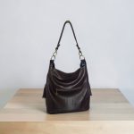 A Slouchy multi pockets eggplant color bag with iridescent hardware and decorative zipper tassels