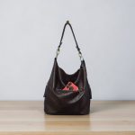 A Slouchy multi pockets eggplant color bag with iridescent hardware and decorative zipper tassels