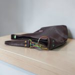 A Slouchy multi pockets eggplant color bag with iridescent hardware and decorative zipper tassels