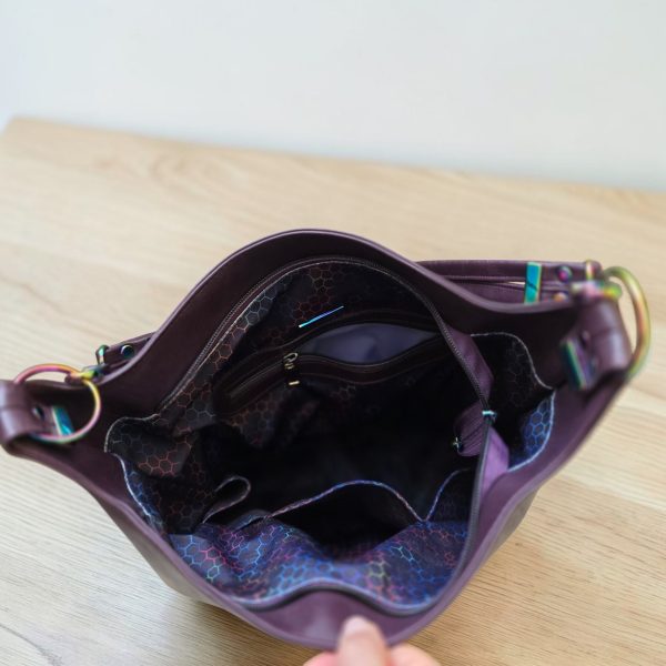 A Slouchy multi pockets eggplant color bag with iridescent hardware and decorative zipper tassels