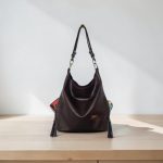 A Slouchy multi pockets eggplant color bag with iridescent hardware and decorative zipper tassels