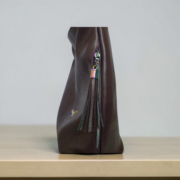 A Slouchy multi pockets eggplant color bag with iridescent hardware and decorative zipper tassels