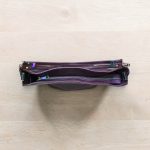 A Slouchy multi pockets eggplant color bag with iridescent hardware and decorative zipper tassels