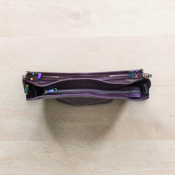 A Slouchy multi pockets eggplant color bag with iridescent hardware and decorative zipper tassels
