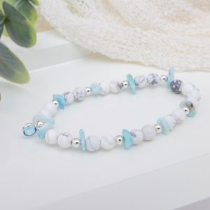 Handmade howlite and larimar chip bracelet with sterling silver beads and an aquamarine birthstone bead centerpiece on a soft, ocean-inspired background.